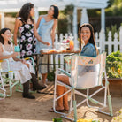 Women gather in a garden, smiling and chatting while seated in floral Freestyle Rockers.