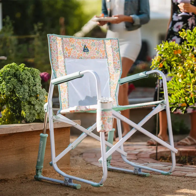 Freestyle Rocker in a colorful floral print sits near greenery with a tumbler in the cup holder.