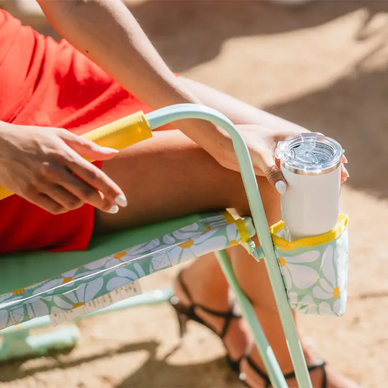 Close-up of a woman in a red dress seated in a GCI Freestyle Rocker Green/Yellow chair with a white tumbler in the cupholder.