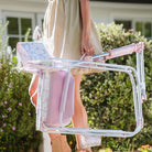 Woman in a tan dress carries a folded pink floral Freestyle Rocker by the handle.
