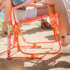 Zoomed view of the rocker’s bright orange frame, spring mechanism, and palm tree tattoo on leg.