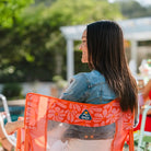 Close-up of the orange floral Freestyle Rocker’s mesh back and logo as a woman relaxes outdoors.