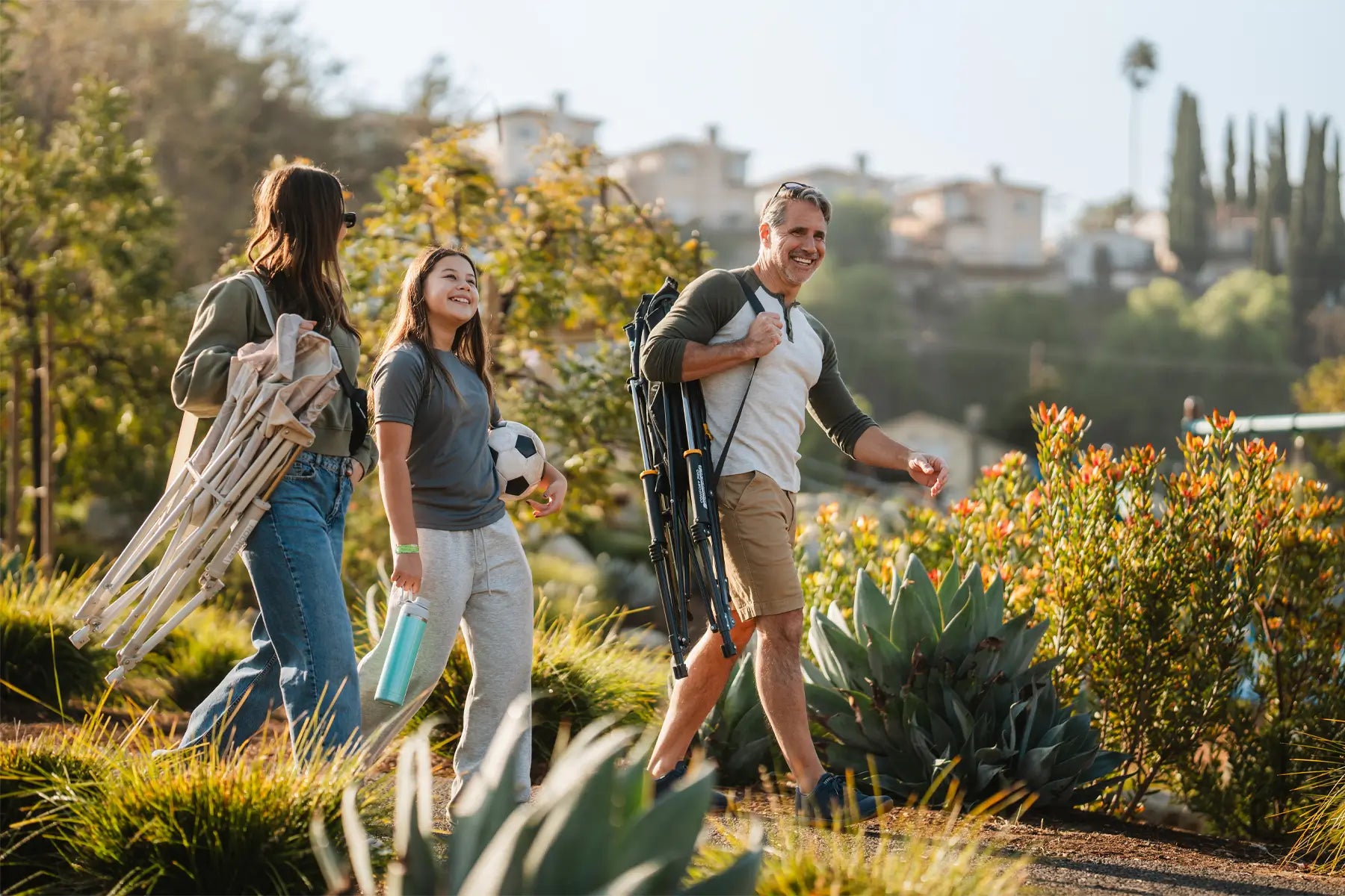 A family walking together on a gravel path while holding comfort pro rockers.