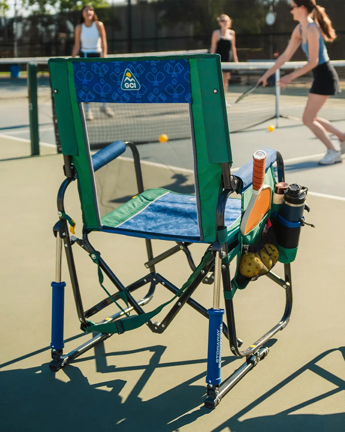 A group playing pickleball next to a stowaway rocker pickleball chair. 